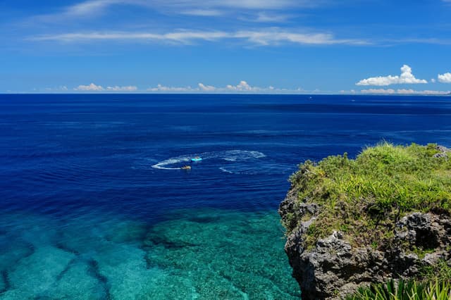 Mar turquesa y cristalino bajo un acantilado verde en Okinawa, Japón