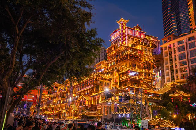 Els edificis sobre pilons de Hongyadong il·luminats de nit sobre el riu, Chongqing
