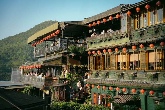 Casa de te de fusta de Jiufen guarnida amb fanalets vermells davant de muntanyes verdes
