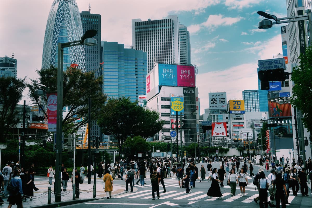 Bustling street scene in Shinjuku, Tokyo with crowds and towering skyscrapers.