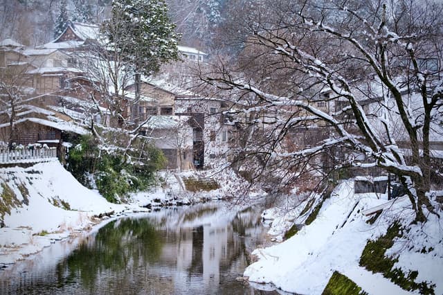 Casas tradicionales de madera junto a un río nevado en Takayama, Japón